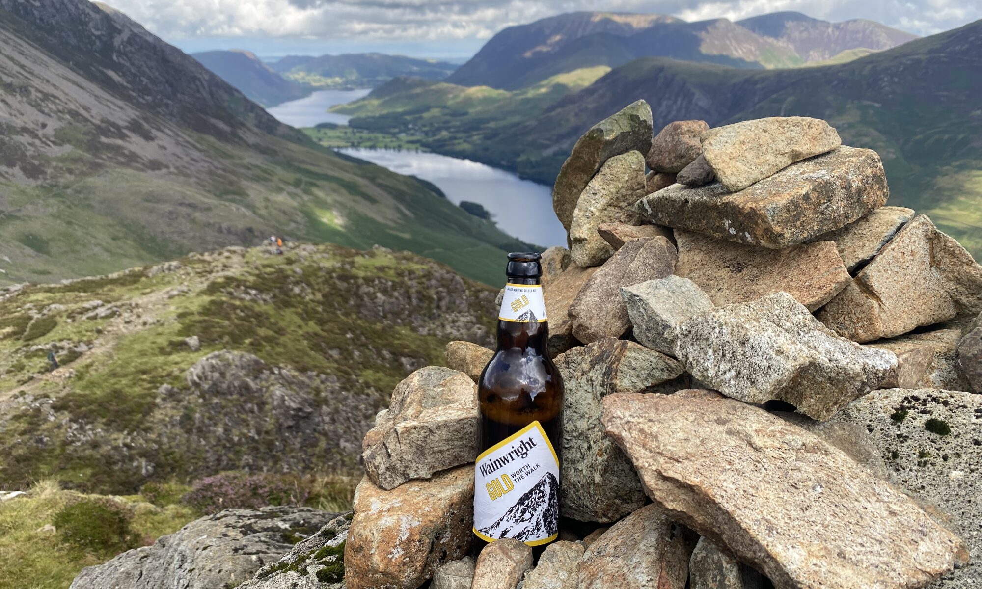 Bottle of Wainwright Gold at the top of Haystacks looking down to Buttermere